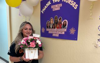 Nurse holding present in front of sign