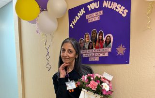 Nurse holding present in front of sign
